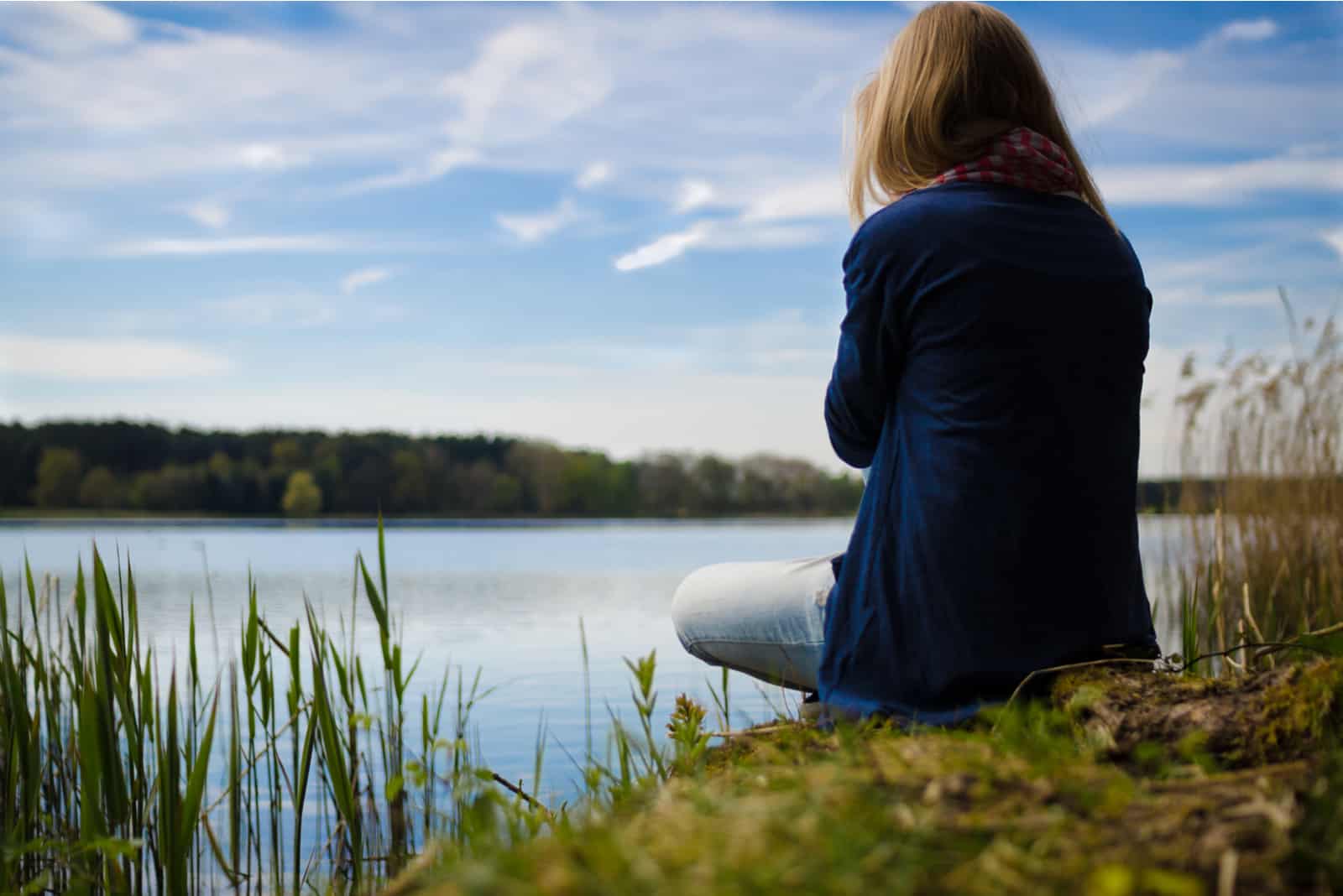 mujer sentada junto al lago