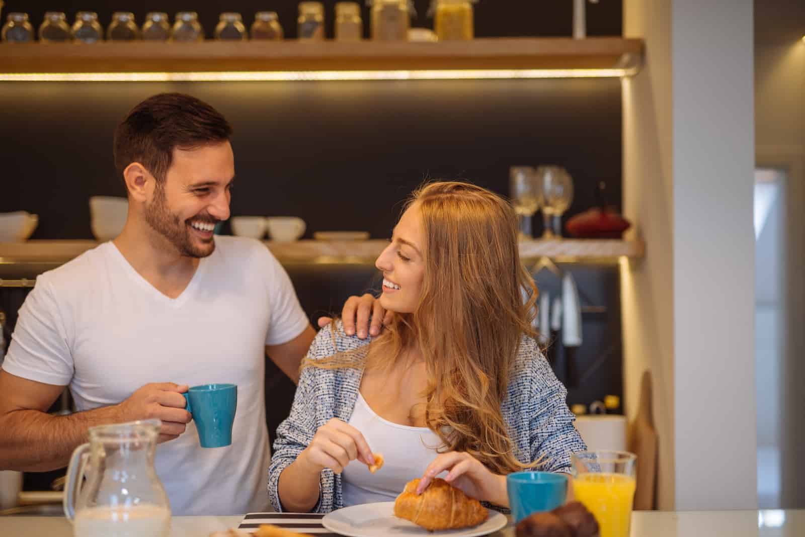 pareja sonriente hablando mientras desayuna en la cocina