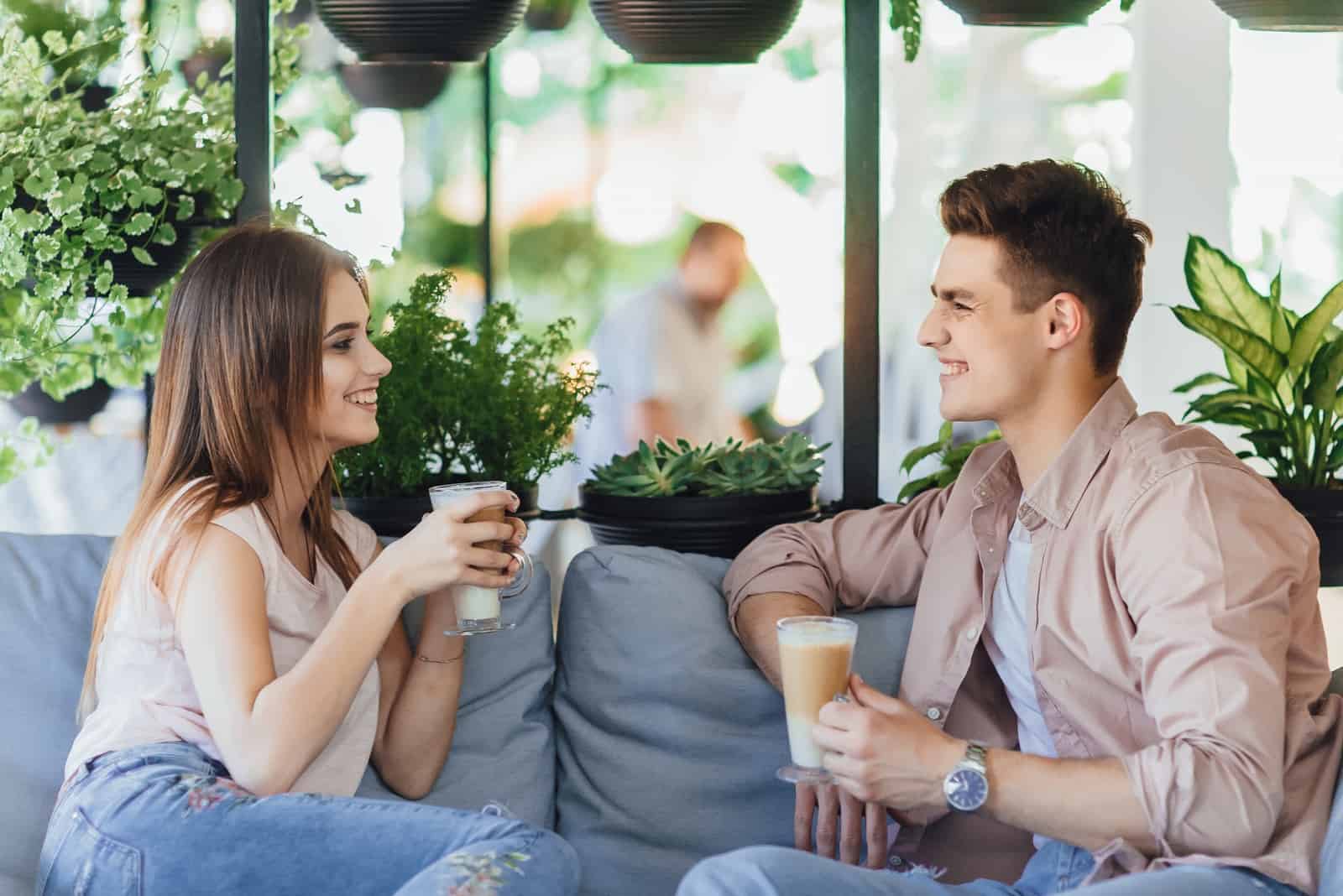 Hombre y mujer tomando café mientras están sentados en un café.