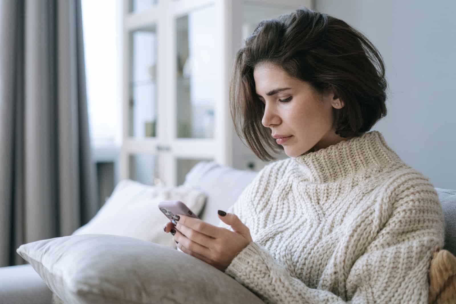 mujer usando un teléfono inteligente mientras está sentada en el sofá