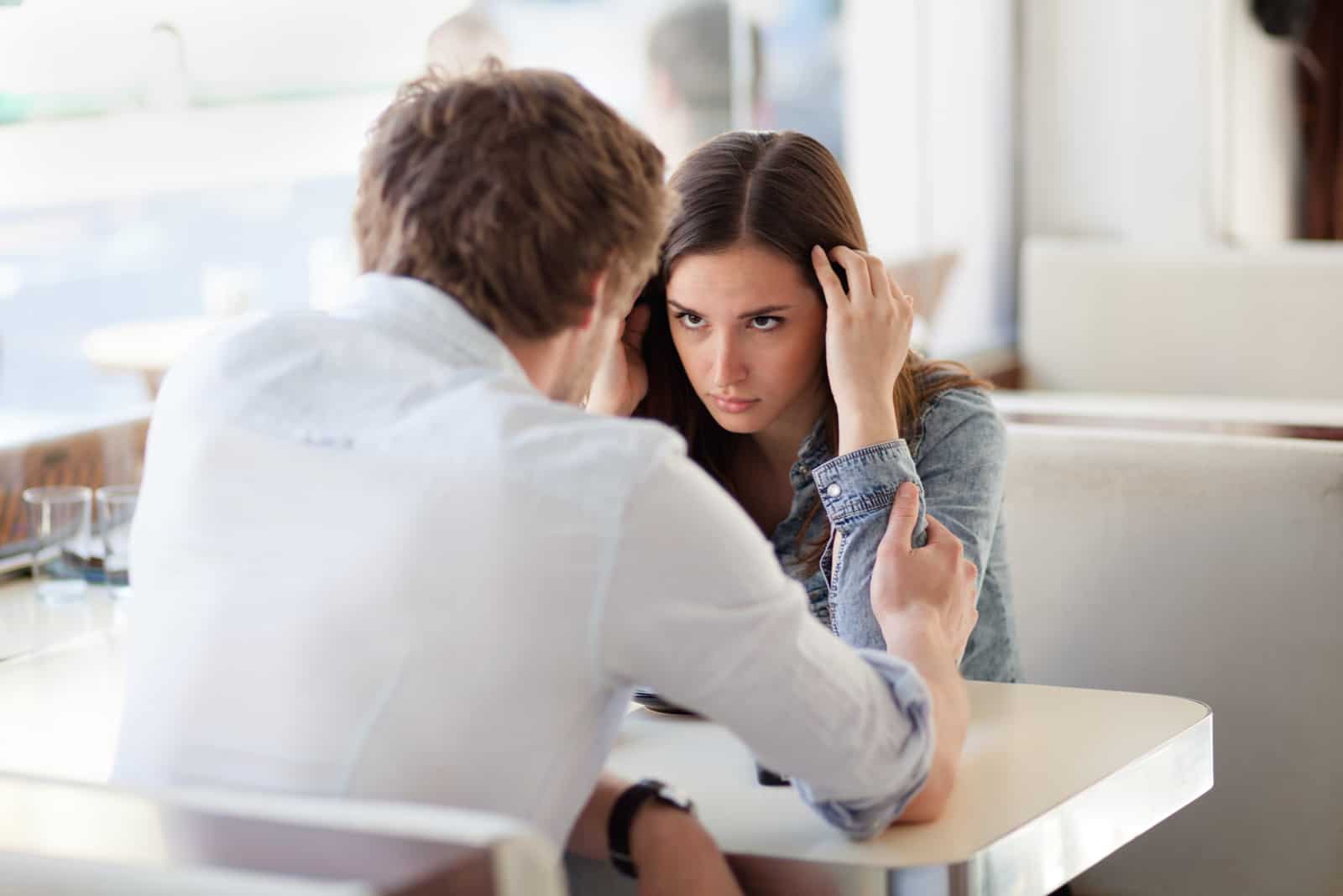 hombre disculpándose con una mujer mientras está sentado en una mesa