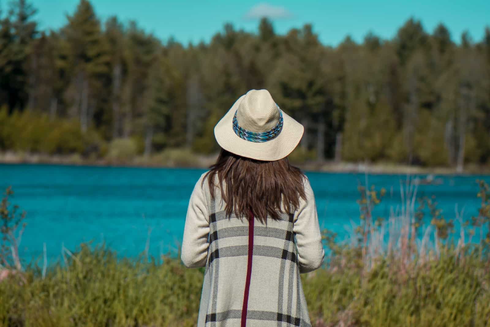 mujer con sombrero mirando un lago