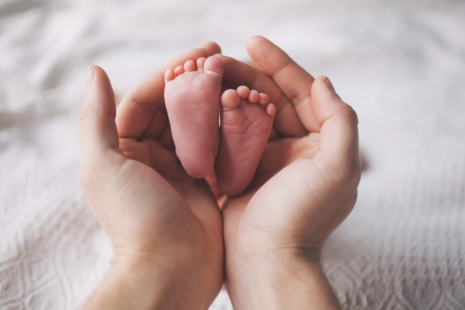 manos sosteniendo pies recién nacidos