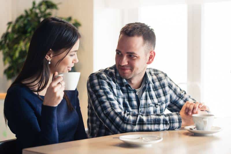 un hombre y una mujer hablando en el café y bebiendo té