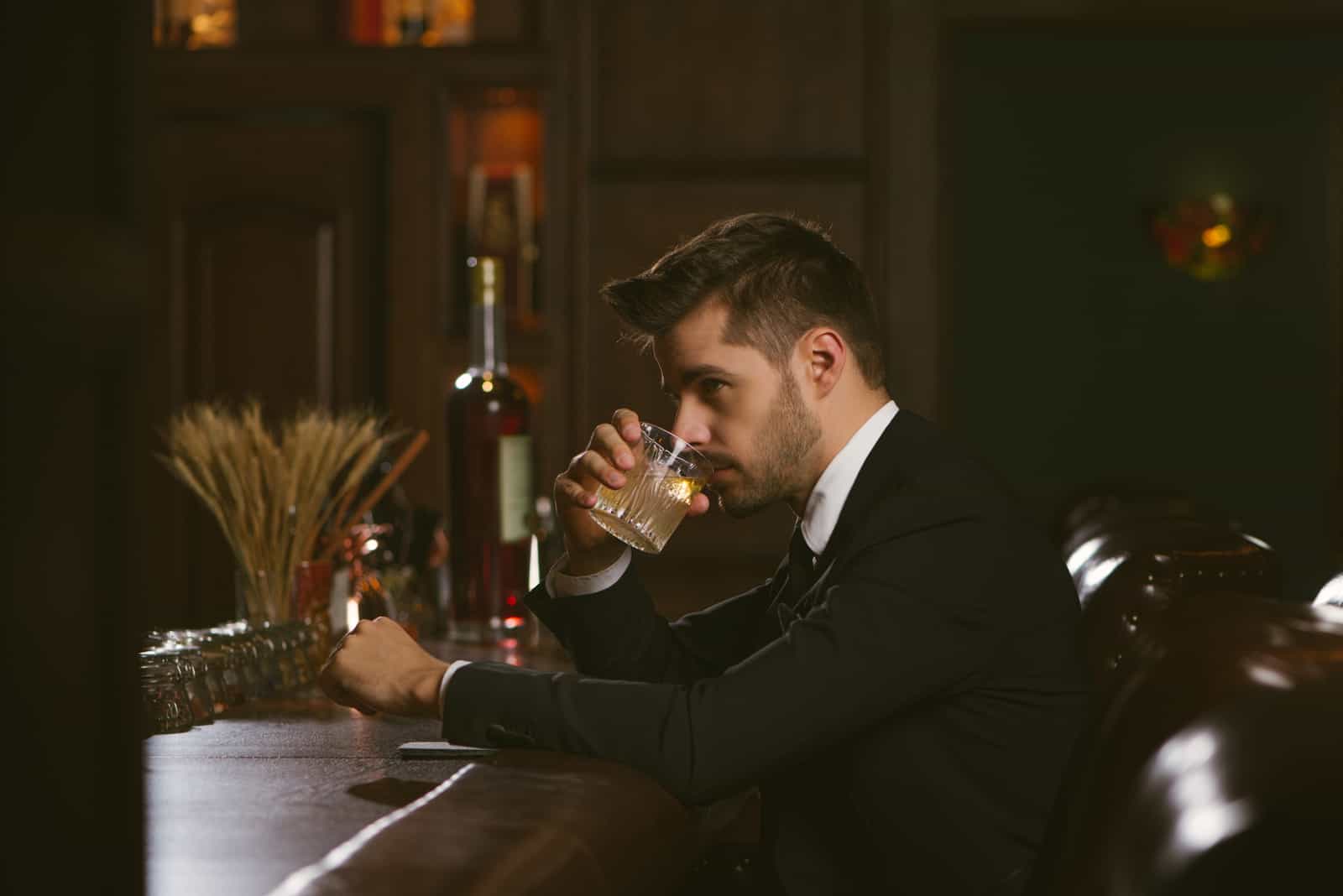 Hombre guapo vestido con un esmoquin negro en un bar de whisky