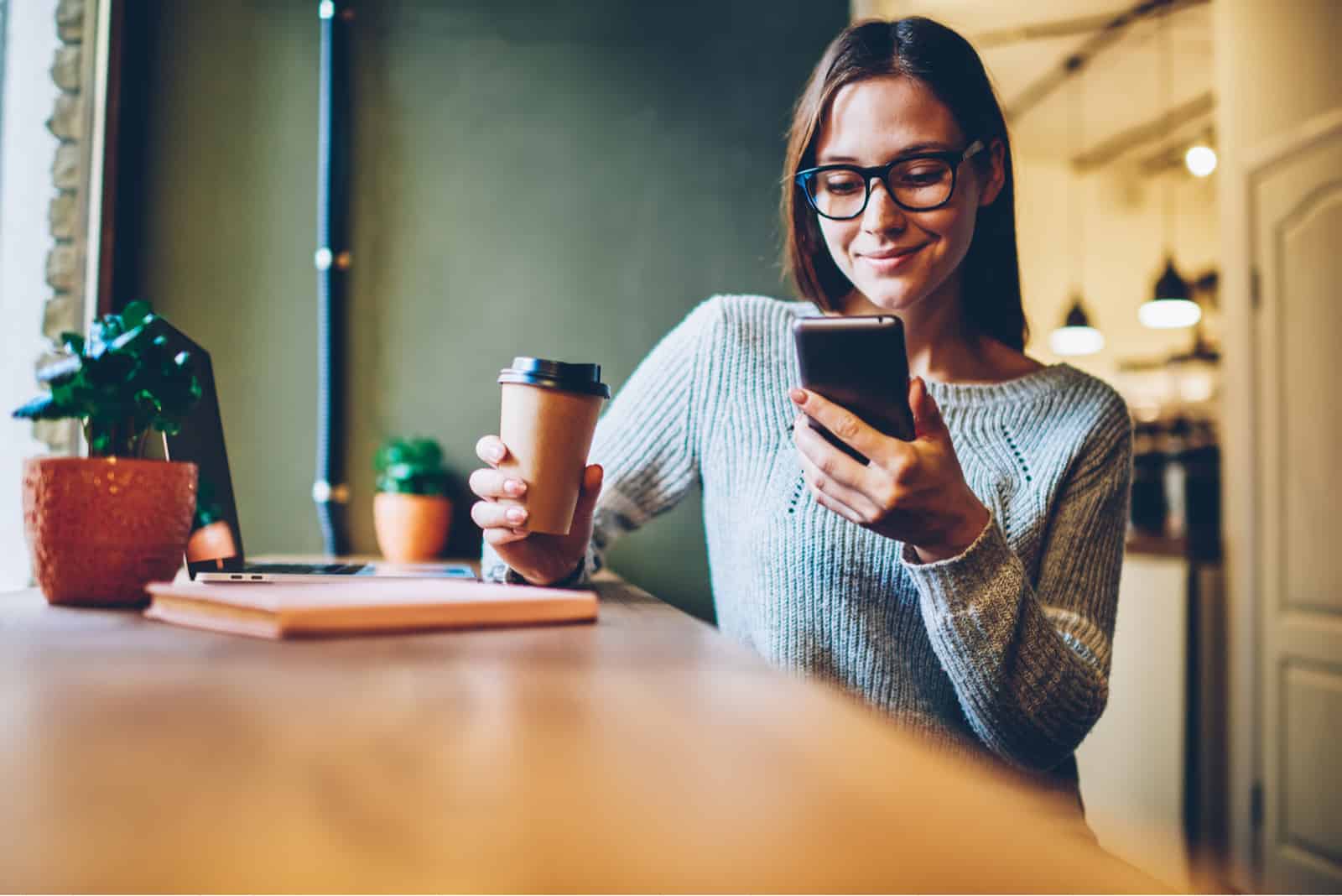 una mujer sentada con café sosteniendo un teléfono en la mano