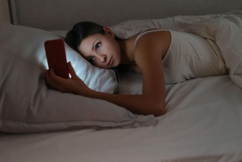 mujer joven en el teléfono en la cama