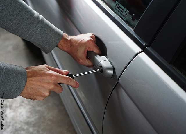 Foto de una persona abriendo la puerta de un auto gris.