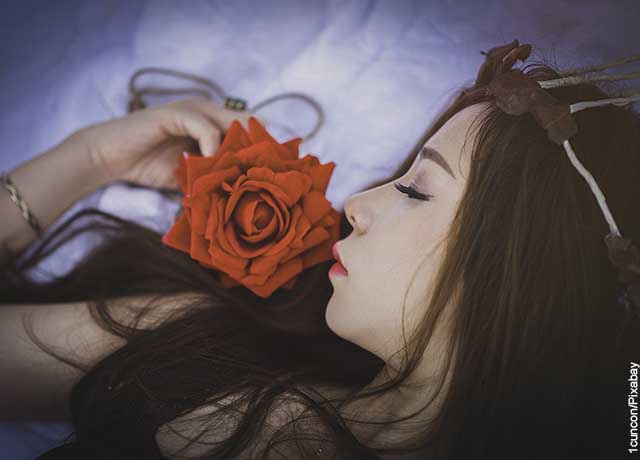 Foto de una mujer durmiendo con una rosa que revela el significado de los sueños