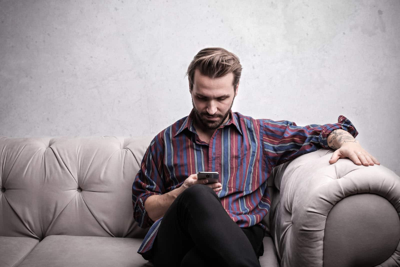 hombre usando un teléfono inteligente sentado en el sofá