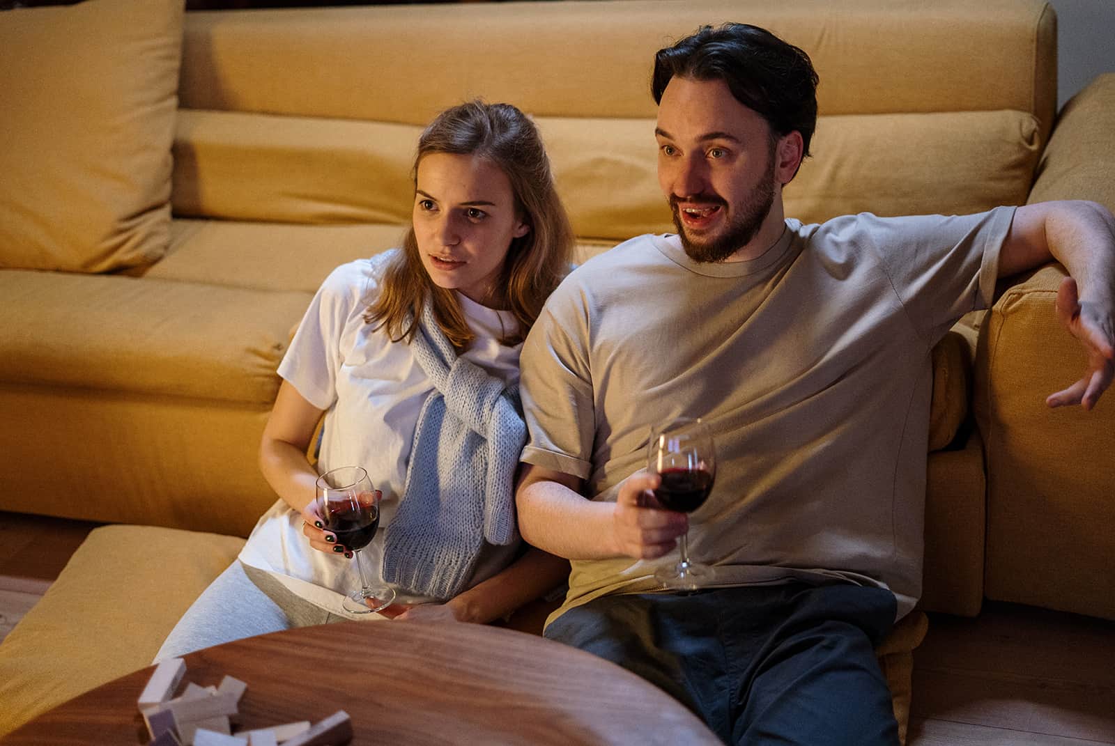 una pareja bebiendo vino en casa viendo una película juntos
