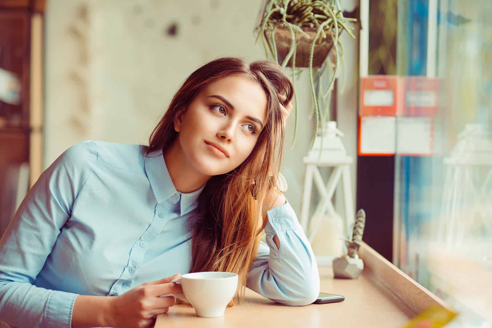 una mujer imaginaria sentada en una mesa tomando café
