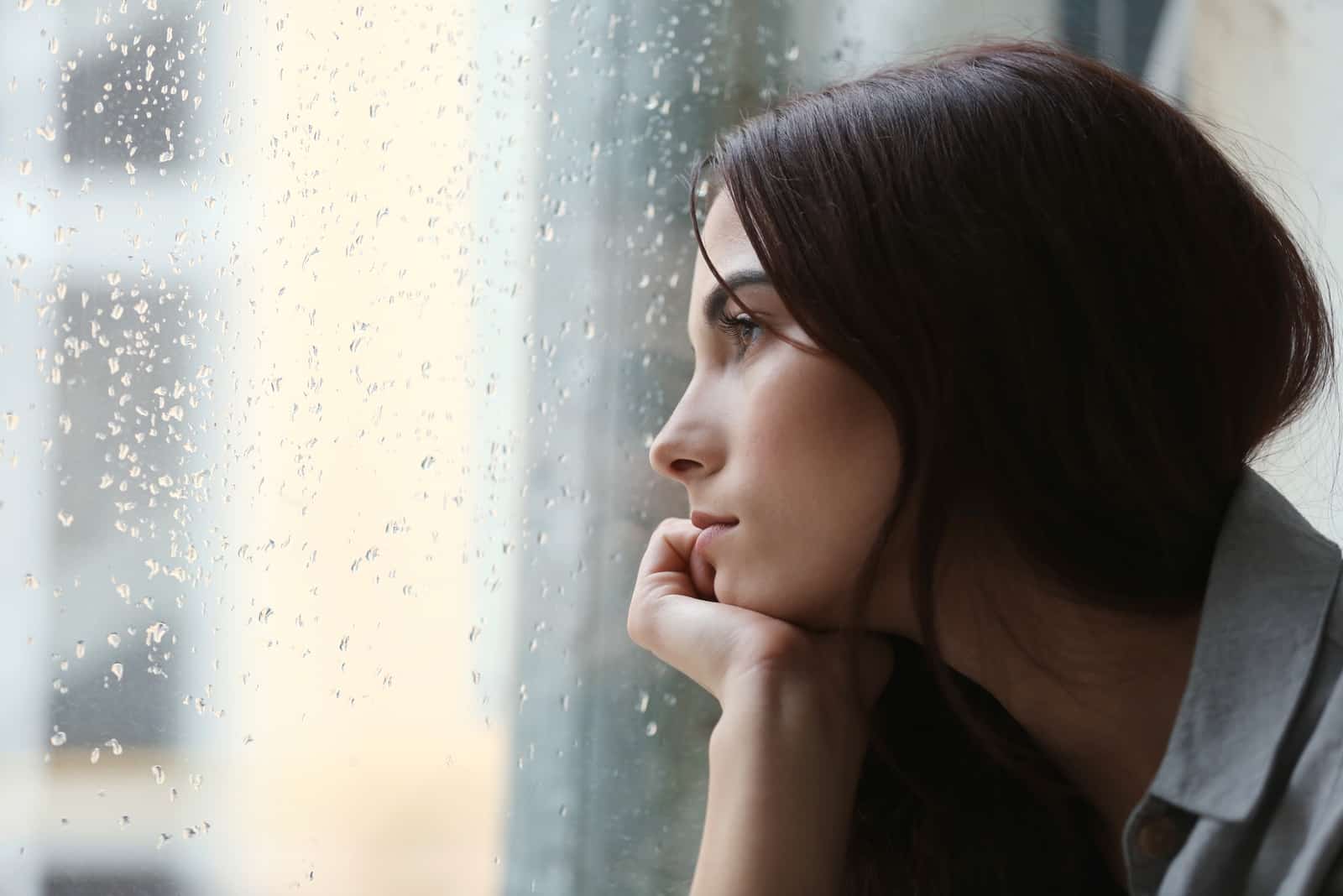 mujer decepcionada se sienta y mira por la ventana