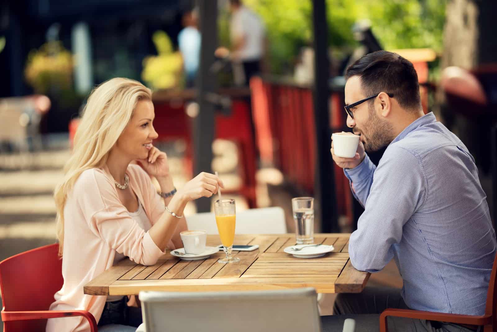 el hombre y la mujer sonrientes se sientan y beben café